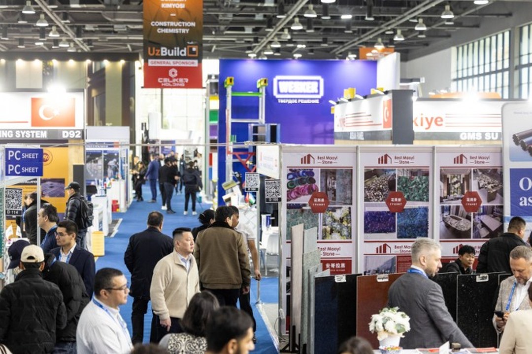 Uzexpocentre NEC 展馆主通道 - 室内展区与室外工程机械展区同期开放，建材、饰面与设备展台沿主通道排布。